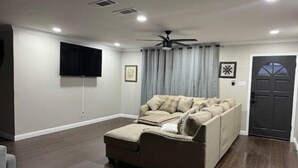 A living room with a sectional sofa, a ceiling fan, recessed lighting, a flat-screen TV, and a door with a window. - Sylvia’s Getaway
 (Longview)