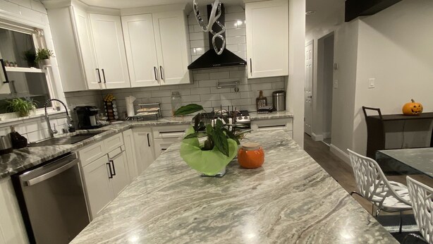 A modern kitchen with white cabinets, a marble countertop, and a stainless steel range hood. - Contemporary Cozy Cottage (Lake Peekskill)
