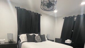 A neatly arranged bedroom with a large bed, a bedside table with a lamp, and a chair. - Contemporary Cozy Cottage (Lake Peekskill)