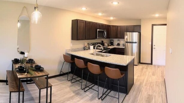 A modern kitchen with dark wood cabinets, stainless steel appliances, and a central island with bar stools.
