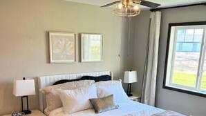A bedroom with a bed, nightstands, a ceiling fan, and a window.