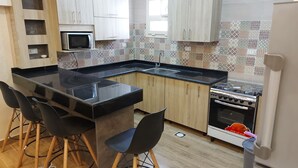 Una cocina moderna con una isla central, taburetes de bar, microondas y horno.