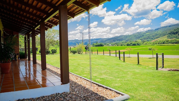 Eine überdachte Terrasse mit Blick auf eine grüne Landschaft und Berge.