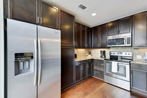 Una cocina moderna con electrodomésticos de acero inoxidable, armarios de madera oscura y salpicadero con motivo de espiga.