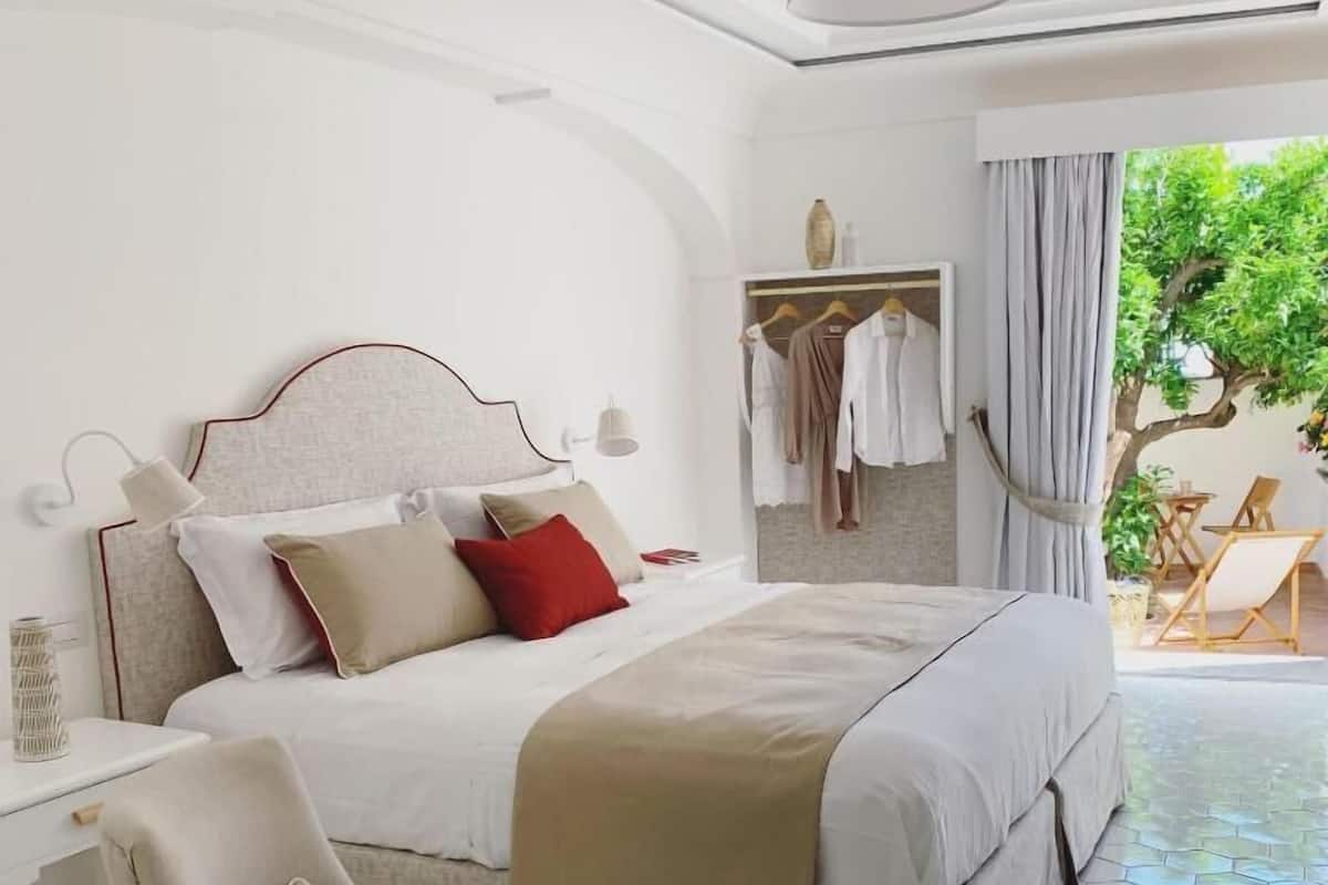 A bedroom with a bed, bedside table, chair, and a view of the outdoors.