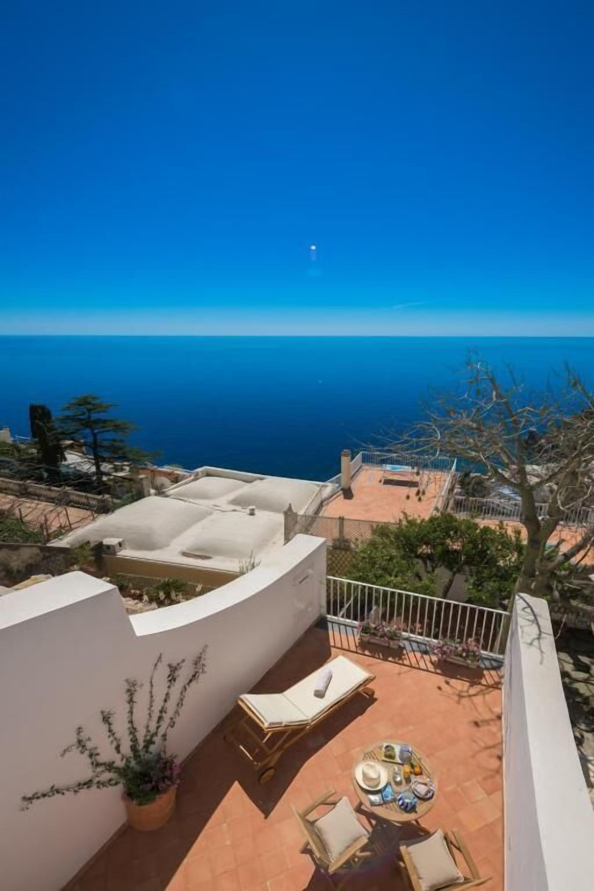 Une terrasse sur le toit offrant une vue sur la mer, des sièges en plein air et des plantes en pot.