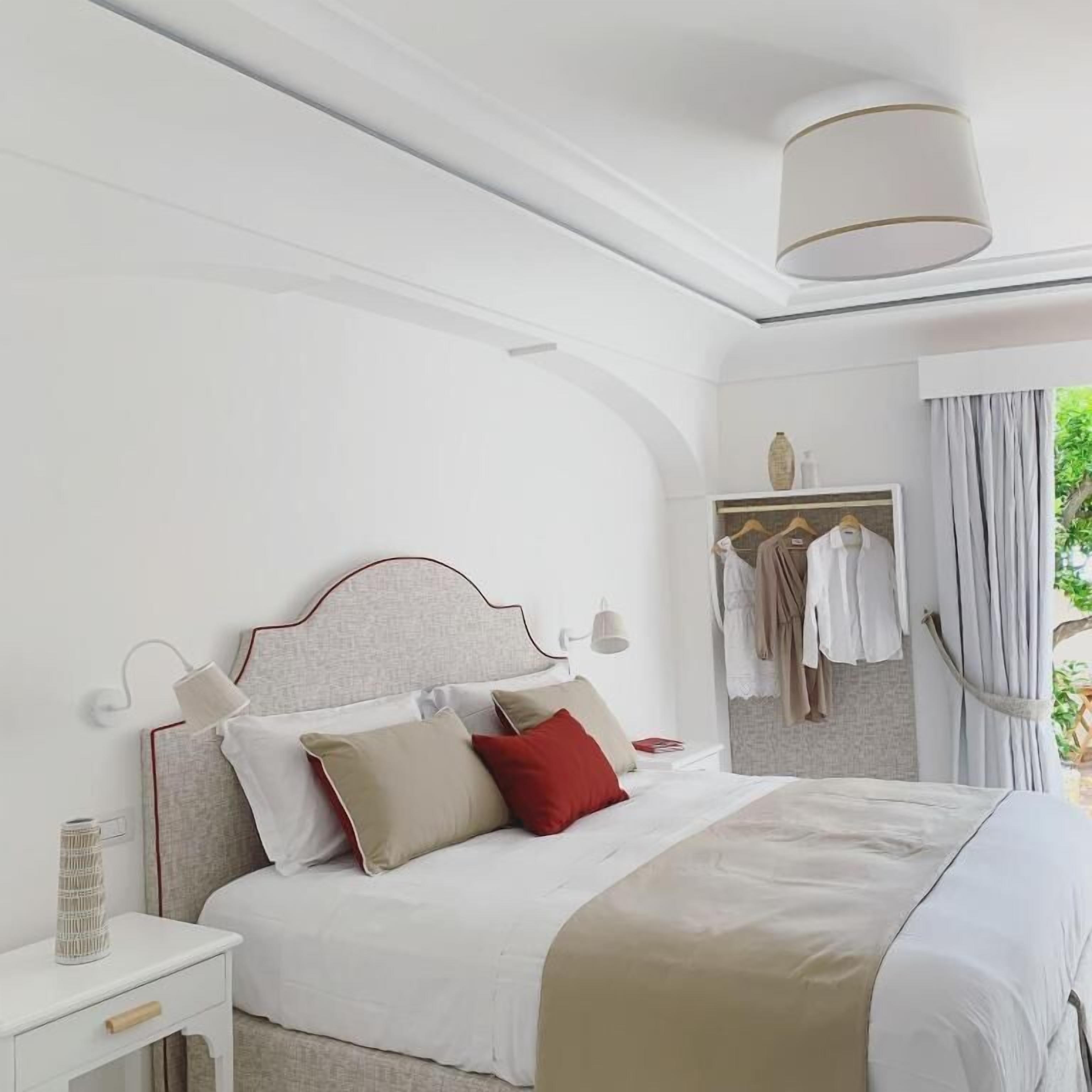 Un dormitorio ordenado con cama, mesita de noche y un armario con ropa colgada.