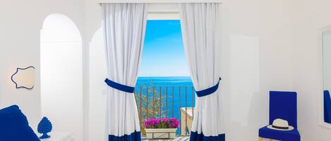 A room with a bed, a chair, and a view of the sea.