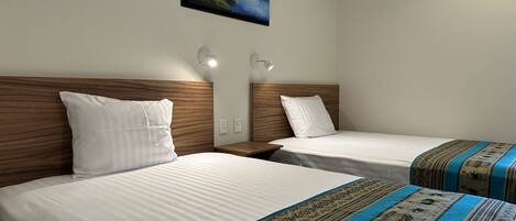 Two single beds with wooden headboards, white bedding, and decorative blue and beige bed runners.