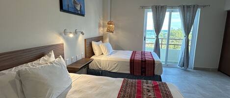 A hotel room with two beds, a ceiling fan, a painting on the wall, and a view through the window.