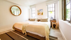 A hotel room with two beds, a round mirror, a painting, and large windows. - Casa Sofi Double bed Room (Miami Beach)