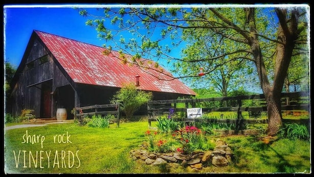 A rustic barn with a red roof, surrounded by a wooden fence and a sign indicating a winery. - Cozy cottage located at our winery at the base of Old Rag  and Shenandoah Park. (Sperryville)
