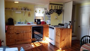 A compact kitchen with wooden cabinets, a dishwasher, a stove, and a refrigerator. - Cozy cottage located at our winery at the base of Old Rag  and Shenandoah Park. (Sperryville)