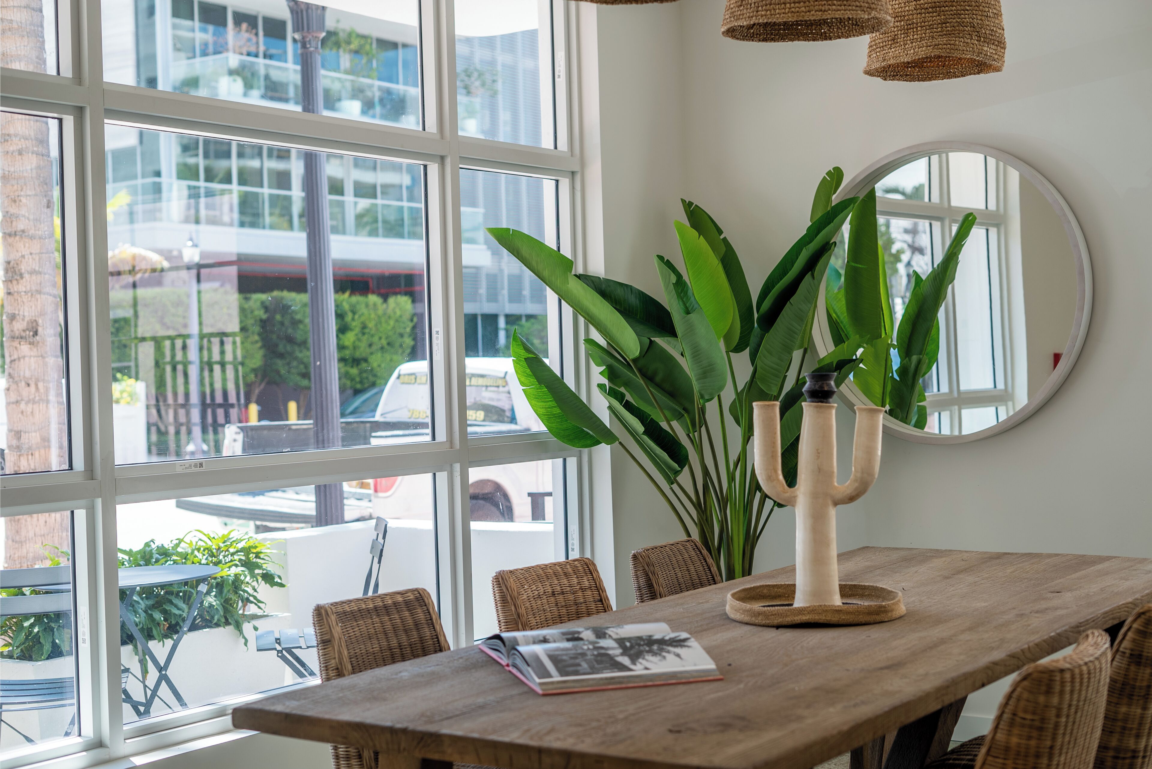 A wooden dining table with a potted plant and a mirror.