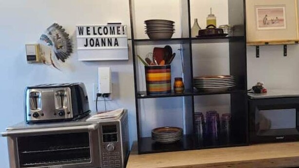 A kitchen with a toaster, microwave, and shelves with dishes and utensils. - Cozy Native American Village! 
HOT TUB! 
PET FRIENDLY!
Fenced-in yards! (Rifle)