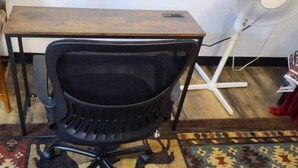A black office chair with a mesh backrest, a wooden table, and a white standing fan. - Cozy Native American Village! 
HOT TUB! 
PET FRIENDLY!
Fenced-in yards! (Rifle)