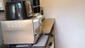A compact kitchen with a refrigerator, microwave, and a small countertop. - Cozy Native American Village! 
HOT TUB! 
PET FRIENDLY!
Fenced-in yards! (Rifle)