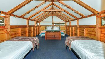 A cabin with two single beds, a central bed, and a wooden ceiling structure.
