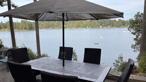 An outdoor patio with a table and chairs, overlooking a lake with boats. - Bremerton Sheltered Waterfront (Bremerton)