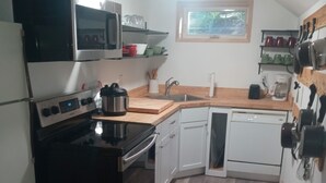 A compact kitchen with a stove, oven, microwave, and dishwasher. There are wooden cabinets and a countertop. - Bremerton Sheltered Waterfront (Bremerton)