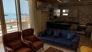Una sala de estar moderna con sofás de cuero, una mesa de centro de madera y vistas al mar a través de grandes ventanales.