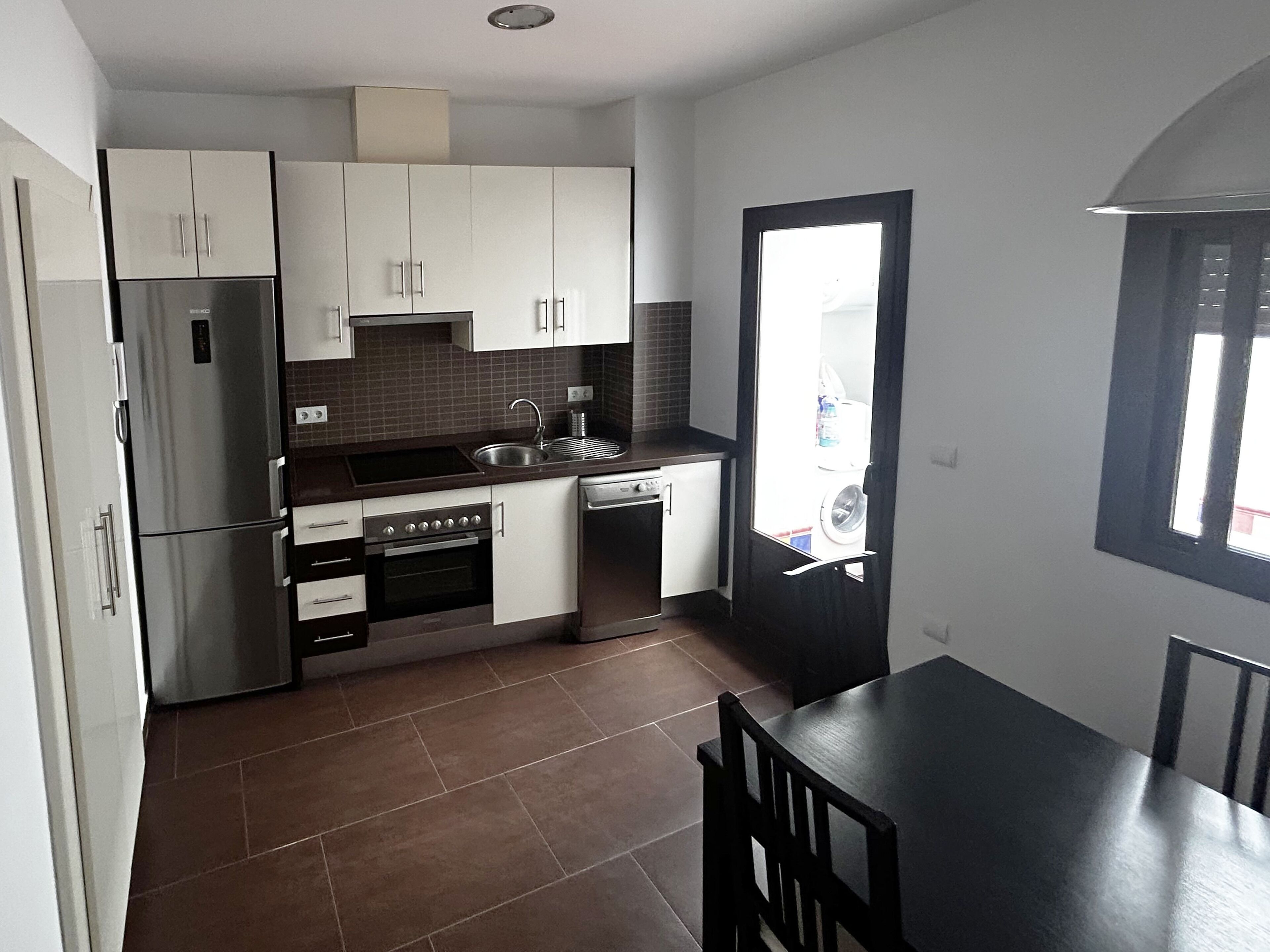 A compact kitchen with a refrigerator, stove, sink, and dishwasher.