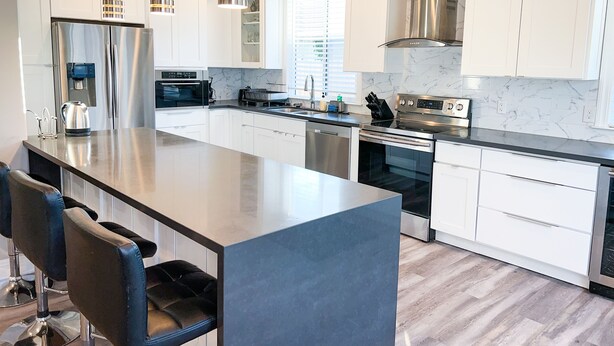 A modern kitchen with white cabinetry, stainless steel appliances, and a central island with bar stools. - Peaceful 3bed3bath 2300sqft Home Centrally Located in Heart of Silicon Valley (Santa Clara)