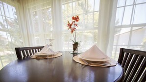Una mesa de comedor puesta con platos, servilletas y un florero.