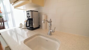 Una cocina con un lavamanos de acero inoxidable, una cafetera y un rollo de toallas de papel en la encimera.