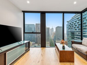 Ein modernes Wohnzimmer mit großem Fernseher, Couchtisch und Sofa.