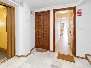 Un pasillo con una puerta de madera, un felpudo y un letrero que indica un sistema de alarma directa.