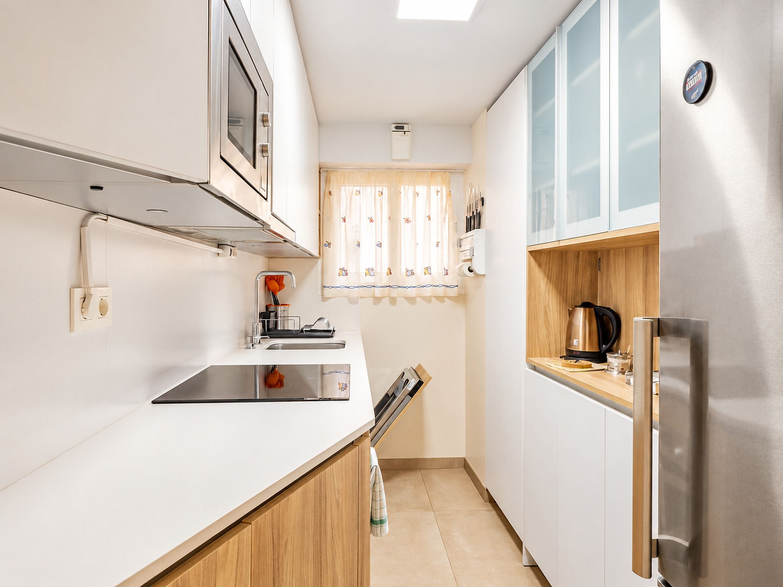 A compact kitchen with a stainless steel refrigerator, a microwave, and a sink.