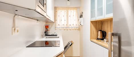 A compact kitchen with a stainless steel refrigerator, a microwave, and a sink.