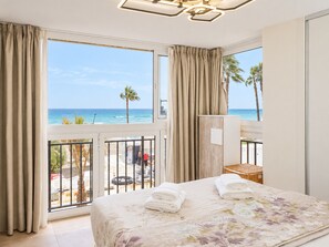 Une chambre d’hôtel avec un lit, un balcon donnant sur la mer et un luminaire au plafond.