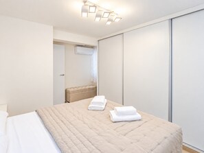 A hotel room with a bed, a bedside table, a wardrobe, and a bathroom visible through an open door.