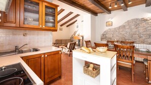 A kitchen with wooden cabinets, a stone wall, and a dining area with wooden chairs and a table.