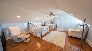 Une chambre spacieuse avec un grand lit, un coin salon avec un fauteuil et un petit canapé.