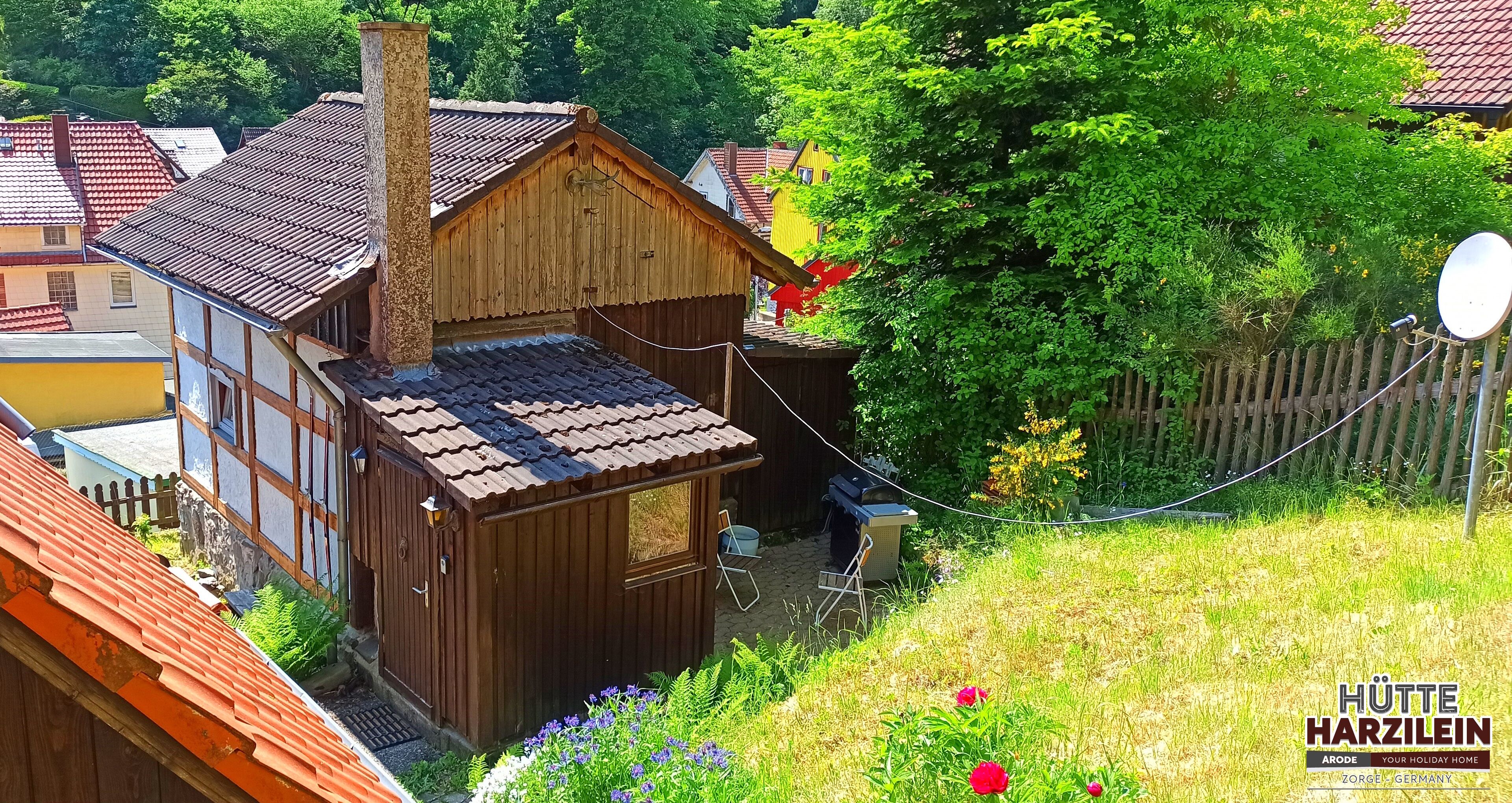 Une maison en bois avec un toit en pente, une cheminée et un petit abri attenant.