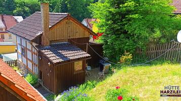 Une maison en bois avec un toit en pente, une cheminée et un petit abri attenant.