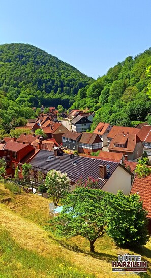 Un village aux maisons traditionnelles, une colline en arrière-plan et un ciel dégagé.