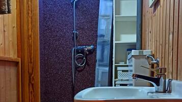 Ein kleines Badezimmer mit einem Holzkosmetikschrank, einer Toilette und einer Duschkabine.