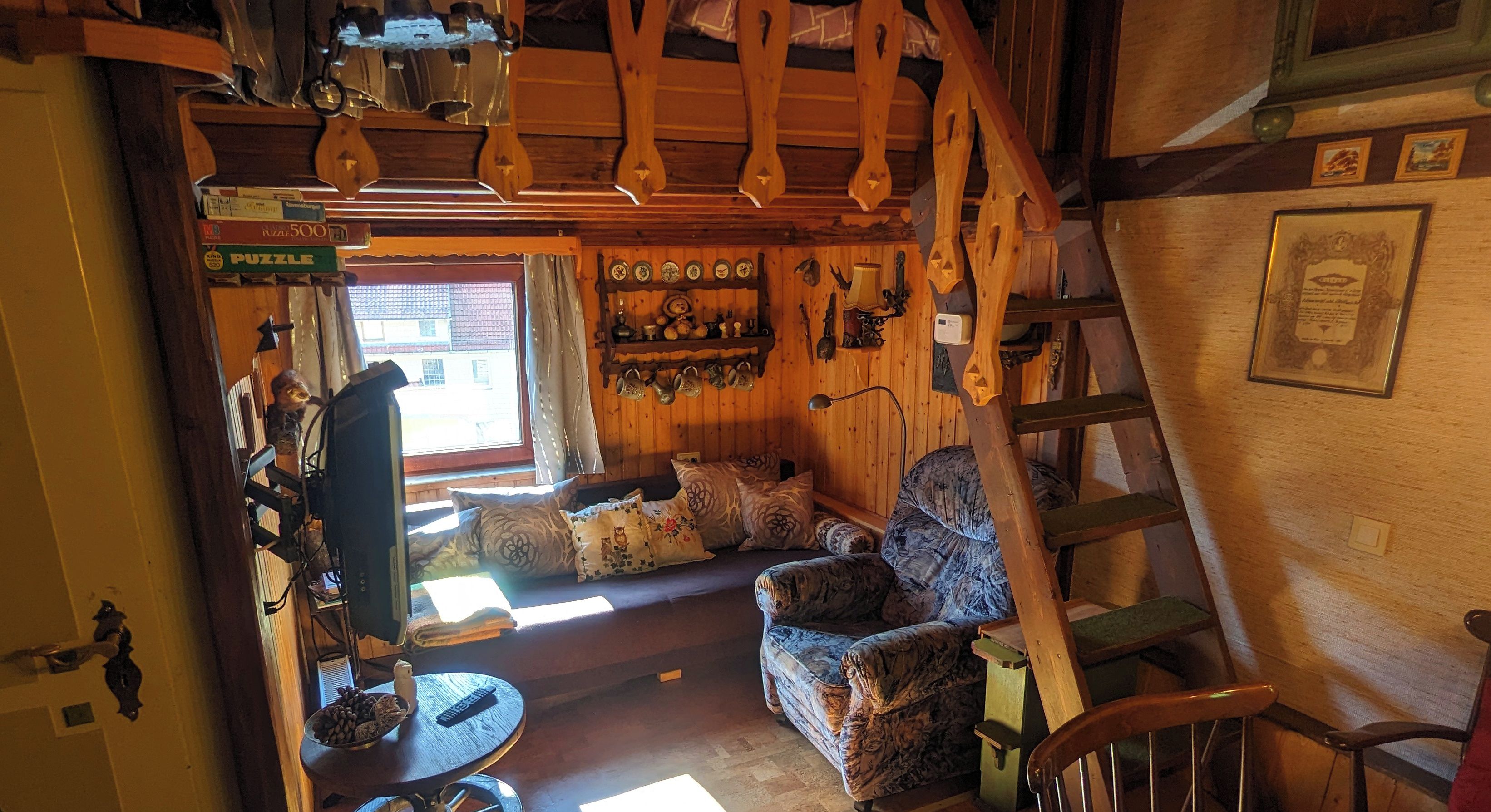 Un interior de madera acogedor con un sofá, sillas, una mesa con ruedas y una escalera.