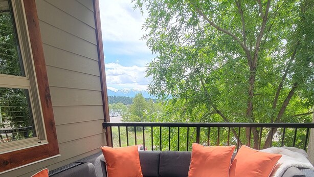 A covered outdoor seating area with a sectional sofa, a glass coffee table, and a patterned rug. - Lakeside Mountain Retreat - 3br, 2 bathroom beachfront condo with pool & hot tub (Invermere)