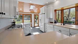 Una cocina moderna con armarios blancos, horno integrado y un amplio ventanal con vistas al exterior.