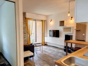 A modern kitchen with a built-in TV, a dining area with a table and chairs, and a large window with curtains.