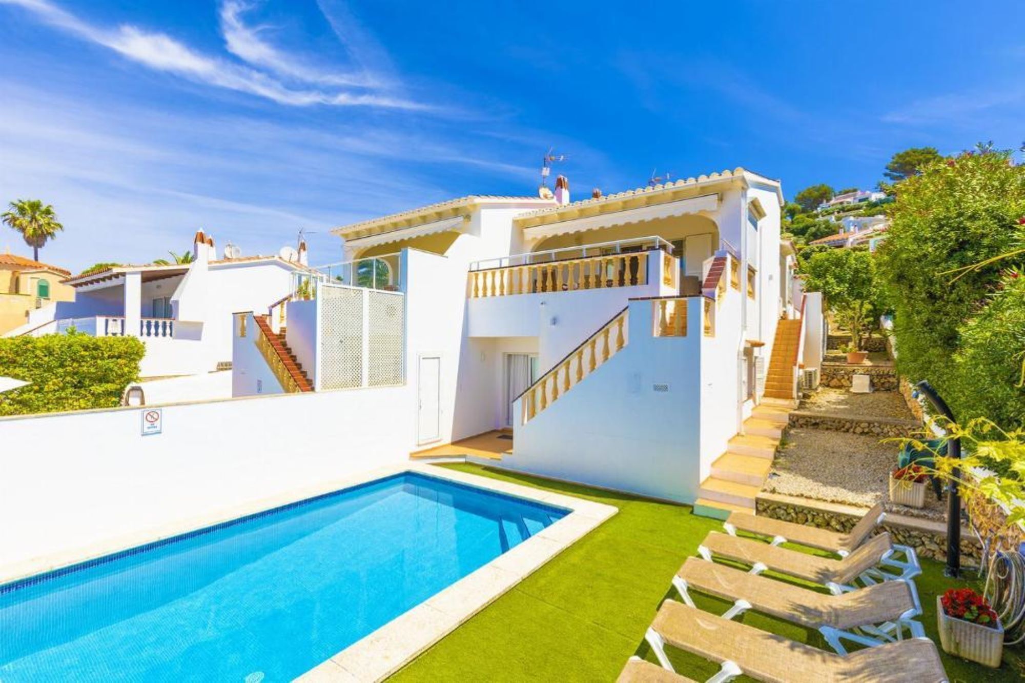 A modern villa with a swimming pool, a staircase leading to a balcony, and a garden area.
