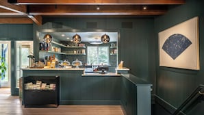 Une cuisine moderne avec des poutres en bois, des luminaires suspendus et une vue sur l’extérieur.