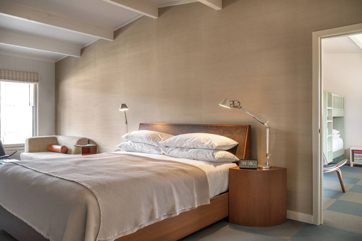 A modern bedroom with a large bed, two bedside tables, and a nightstand with a clock.