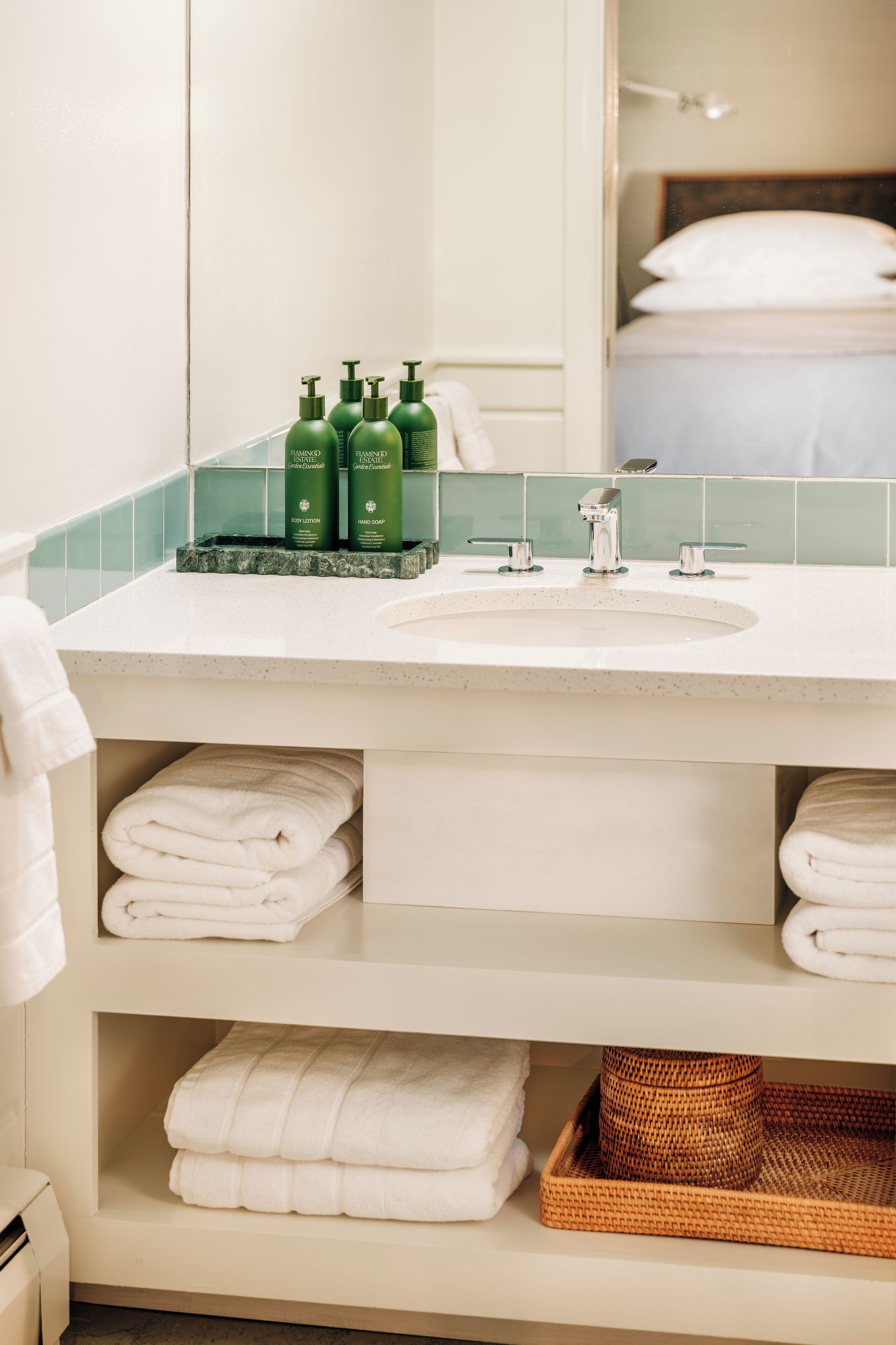 A bathroom with a white sink, green toiletries, and neatly folded towels.