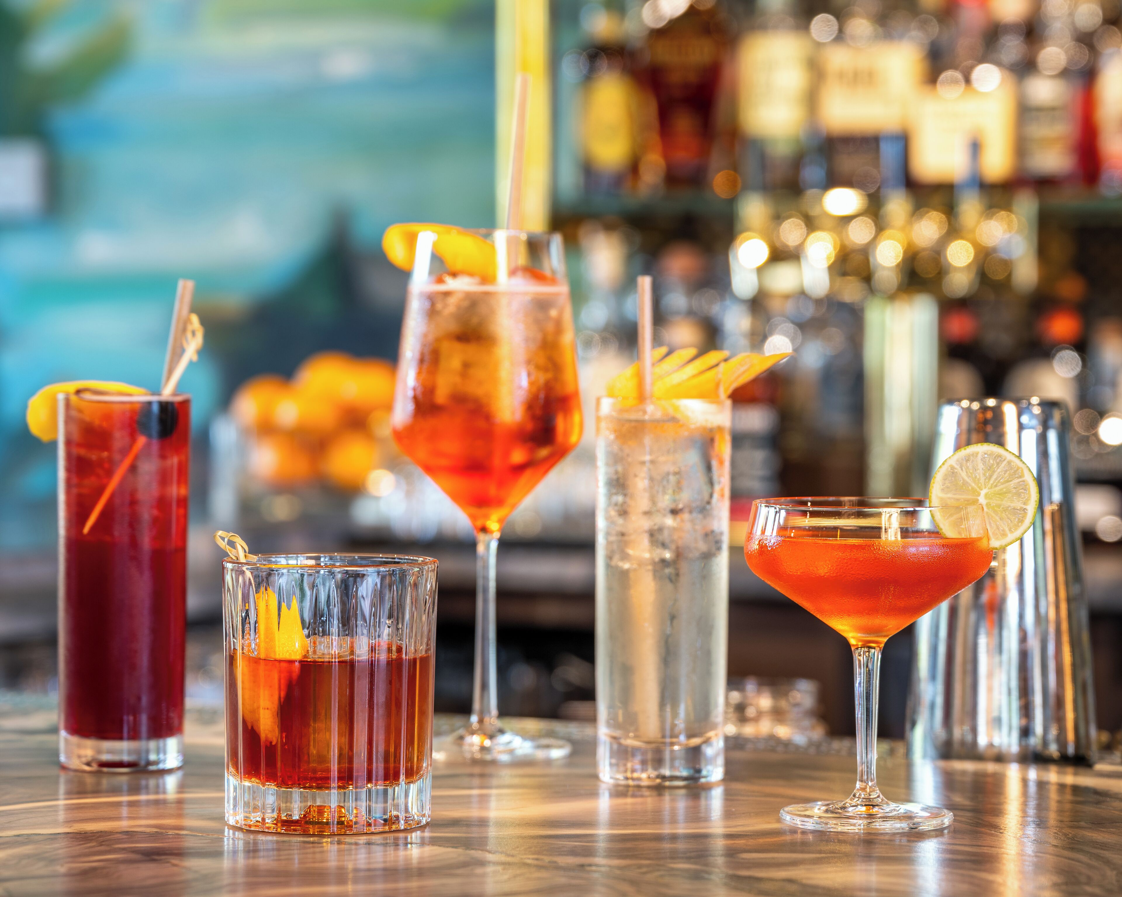 A bar with various drinks, including cocktails and a non-alcoholic option, with a blurred background suggesting a busy environment.